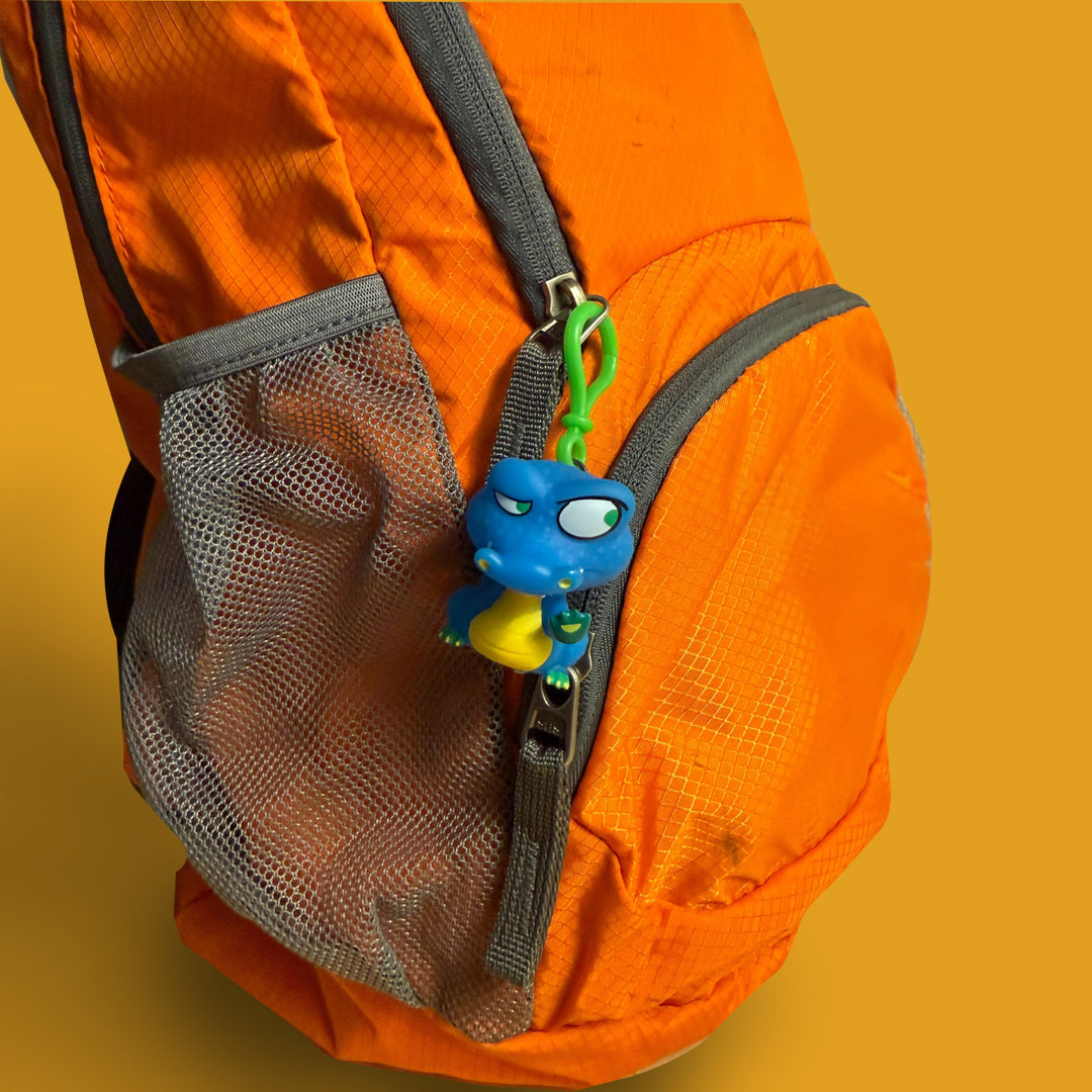 Orange backpack with a gray mesh pocket and a blue character keychain on an orange background